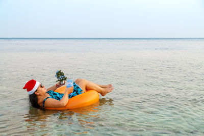 Man relaxing in sea against sky