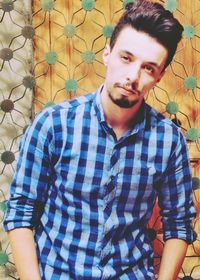 Portrait of young man standing against wall