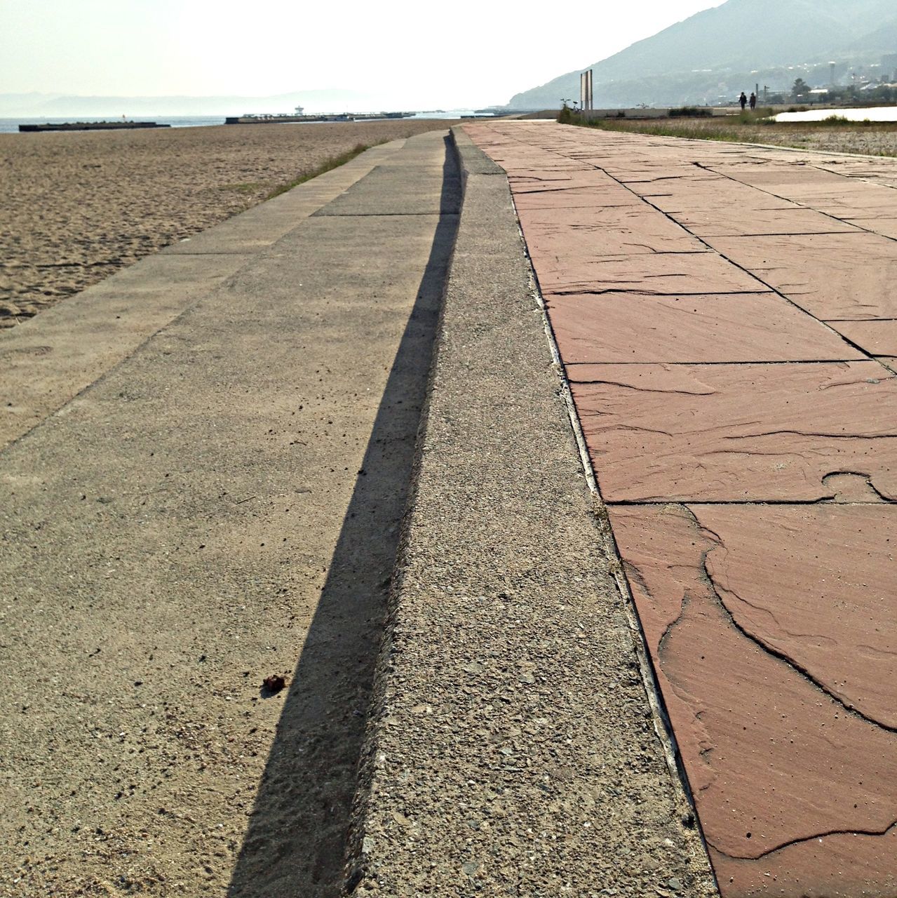 the way forward, diminishing perspective, vanishing point, transportation, sand, road, sunlight, sky, beach, tranquility, day, asphalt, shadow, road marking, tranquil scene, outdoors, surface level, high angle view, empty, tire track