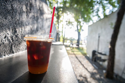 Iced black americano coffee mixed with yuzu juice in plastic glass on wooden table of outdoor cafe 