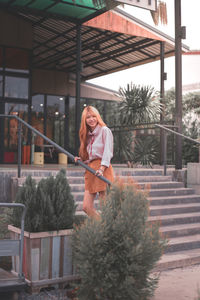 Portrait of happy woman standing against plants