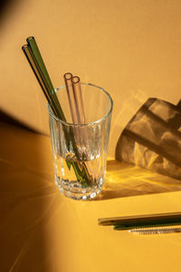 Reusable glass straws in glass with water on beige neutral background eco-friendly drinking straw