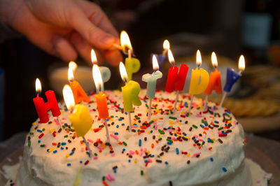 Cropped hand of person burning candle on birthday cake