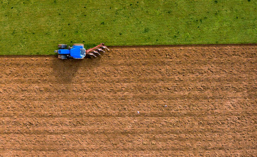 Aerial high angle view of tractor ploughing field