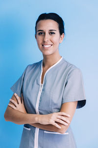 Portrait of smiling doctor with arms crossed standing against wall