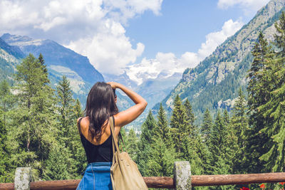 Rear view of woman photographing mountains