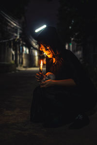 Side view of woman holding lit candle at night