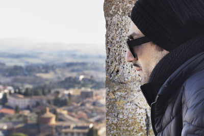 Portrait of young man looking at city during winter