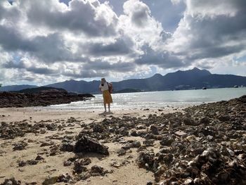 Woman standing on beach against sky