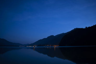 Scenic view of lake against blue sky at dusk