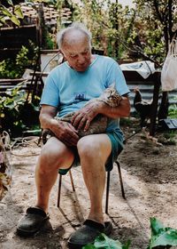 Old man sitting holding his cat