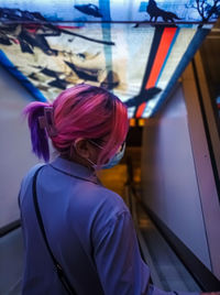 Side view of young woman going down through the escalator.