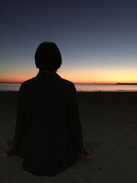 Rear view of silhouette woman looking at sea against clear sky