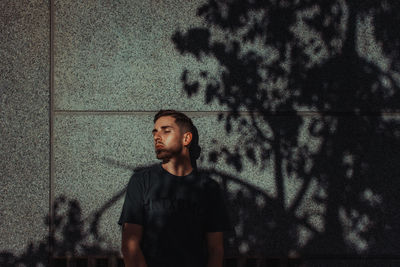 Portrait of young man standing against wall