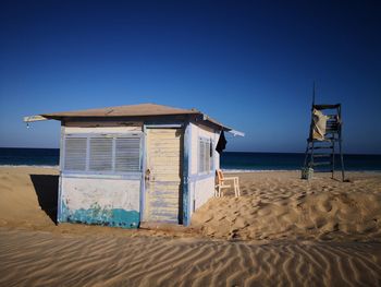 Lifeguard hut on beach against clear blue sky