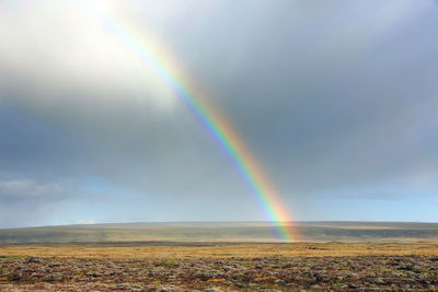 Scenic view of rainbow over landscape against sky
