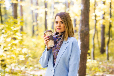 Portrait of young woman standing in forest during autumn