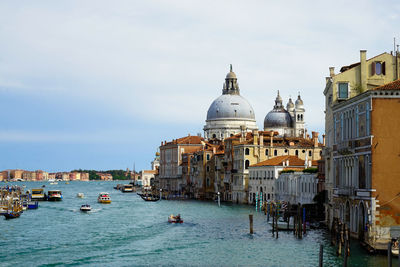 View of buildings by canal against sky