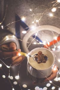 Close-up of hand holding illuminated coffee on table