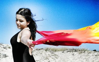 Side view of young woman against blue sky
