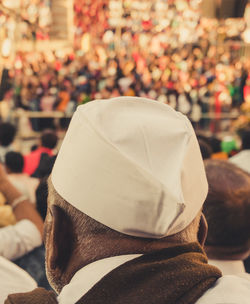 Close up of an old indian man wearing a cap at the stadium amidst the crowd