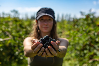 Portrait of woman holding fruit on field