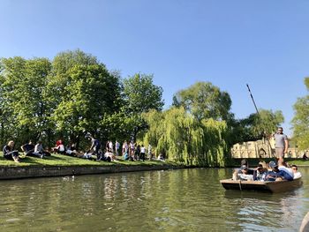 People on boats in river against sky