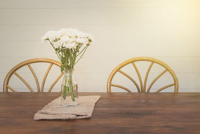 Close-up of flower vase on table against wall at home