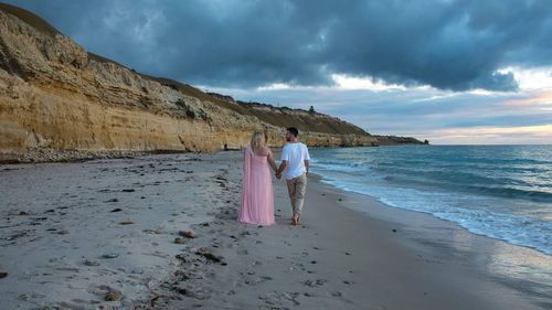 Rear view of couple standing on beach