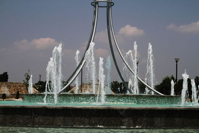 Fountain in city against sky