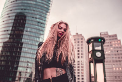 Portrait of young woman standing against skyscrapers