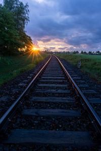 Railroad tracks against sky during sunset