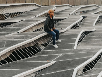 Full length of man sitting on built structure