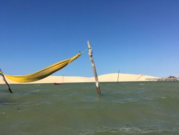 Sailboat in sea against clear blue sky