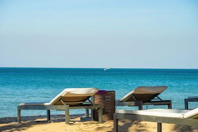 Chairs on beach against clear sky