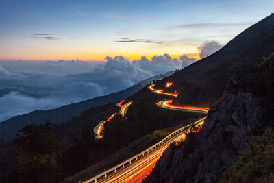 Light trails on road against sky during sunset