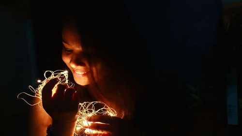 Portrait of woman holding illuminated light in the dark