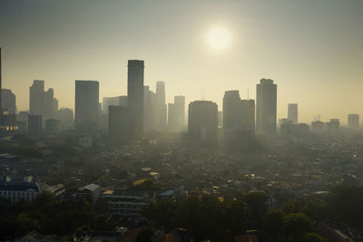 Buildings in city against clear sky during sunset