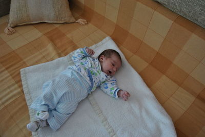 Close-up of cute baby lying on bed at home