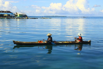 People on boat in sea against sky