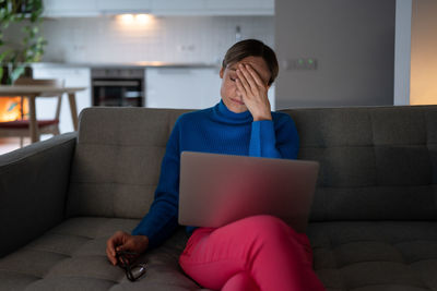 Young woman having headache looks with tired expression after working on business project at home