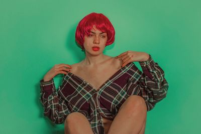 Portrait of young woman against green background