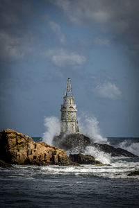 Lighthouse by sea against sky