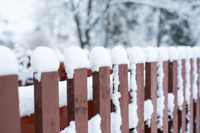 Close-up of wooden fence covered in snow during winter season.