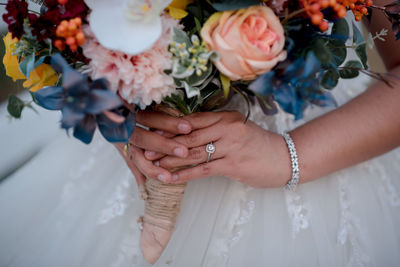 Midsection of bridegroom holding bouquet