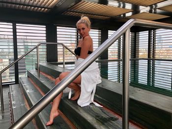 Portrait of beautiful woman sitting on staircase against swimming pool