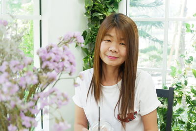 Portrait of smiling woman sitting by plants at home