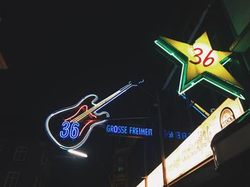 Low angle view of road sign against clear sky at night