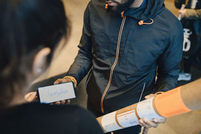 Man holding package while looking at customer's signature on mobile phone