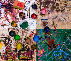 High angle view of multi colored paints and brushes on table